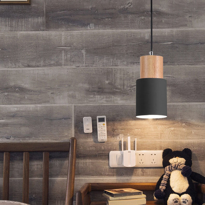 Schwarze Hängelampe aus Holz über Nachttisch mit Büchern und Teddybär, modernes Design.