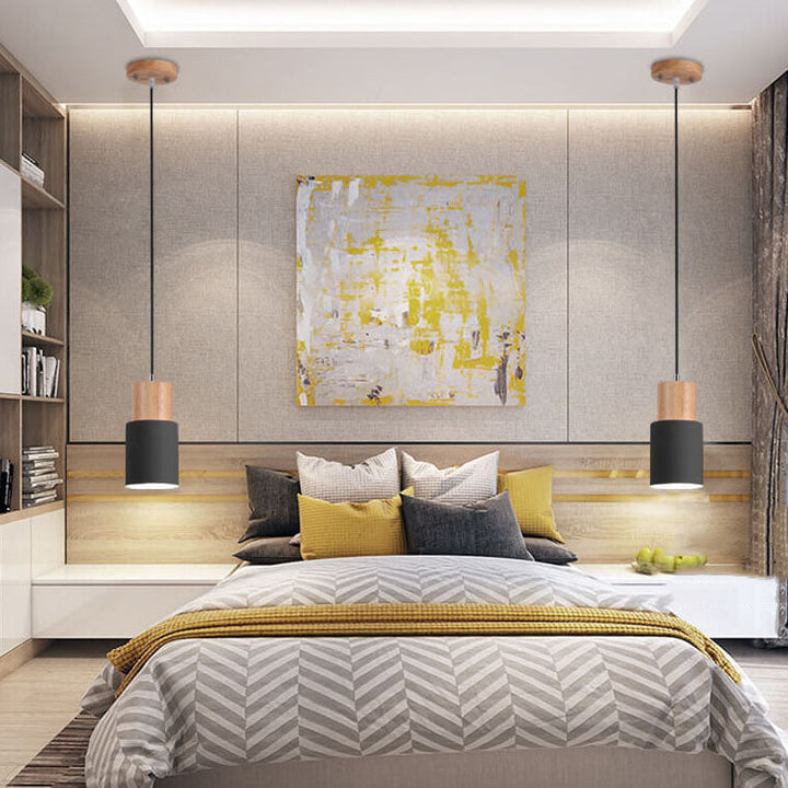 Moderne Schlafzimmerbeleuchtung, schwarze Pendelleuchten, graues Bett, gelbe Akzentkissen.