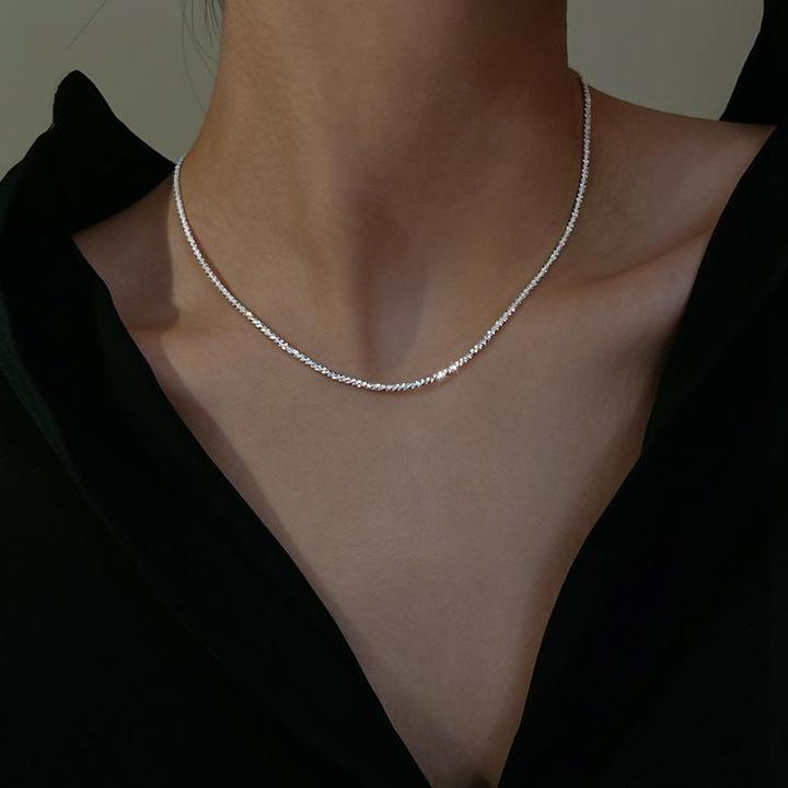 Silberne Halskette auf schwarzem Oberteil, elegantes Schmuckdesign für Damen.