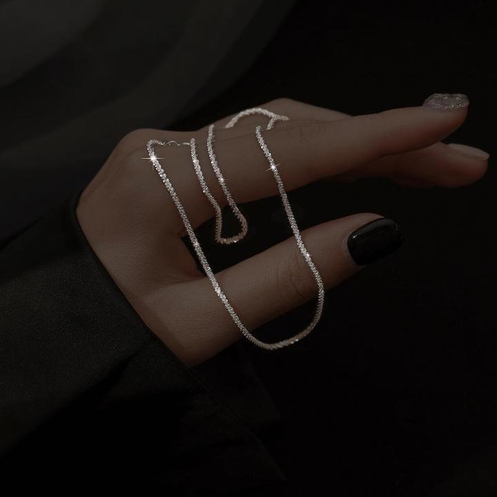 Silberne Halskette auf Hand, elegantes Schmuckdesign, funkelnd, Damenaccessoire.