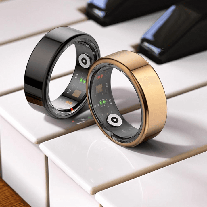 Zwei Smart-Ringe, schwarz und gold, auf Klaviertasten, mit digitaler Anzeige und Sensoren.