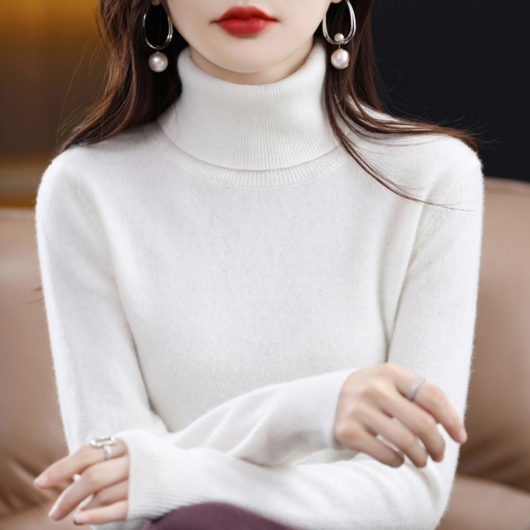 Frau in weißem Rollkragenpullover, elegante Perlenohrringe, modisches Herbstoutfit.