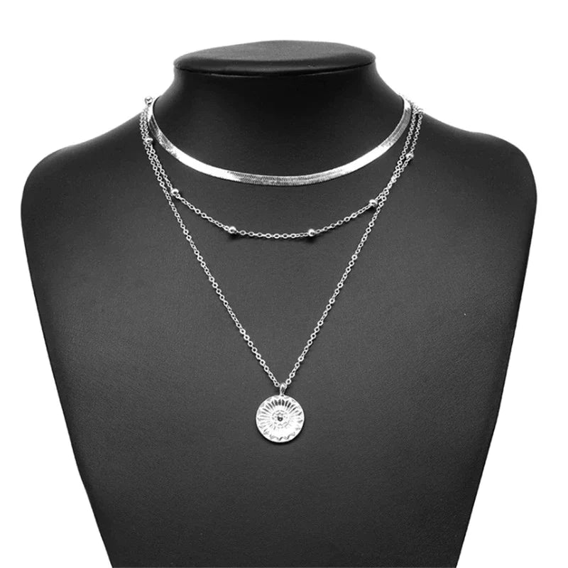 Silberne Halskette mit Sonnenanhänger auf schwarzem Schmuckständer, modisches Accessoire.