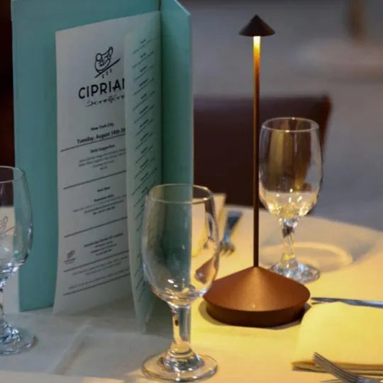 Tisch mit Weingläsern, Speisekarte und moderner Tischlampe in einem Restaurant.