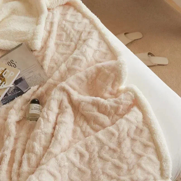 Weiche beige Kuscheldecke auf Bett, mit Zeitschriften und Parfümflasche, gemütliches Schlafzimmer.