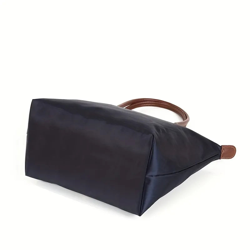 Dunkelblaue Handtasche aus Nylon mit braunen Ledergriffen, stilvoll und geräumig.