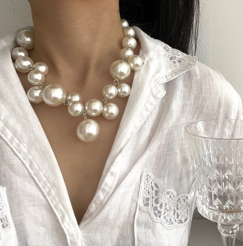 Frau mit eleganter Perlenkette, weißes Hemd, Kristallglas, Schmuck für Hochzeiten.