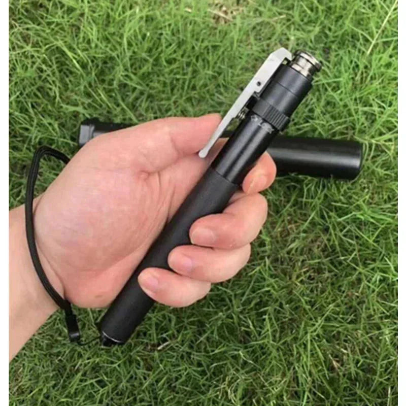Schwarze taktische Taschenlampe, tragbar, in Hand gehalten, auf grünem Gras.