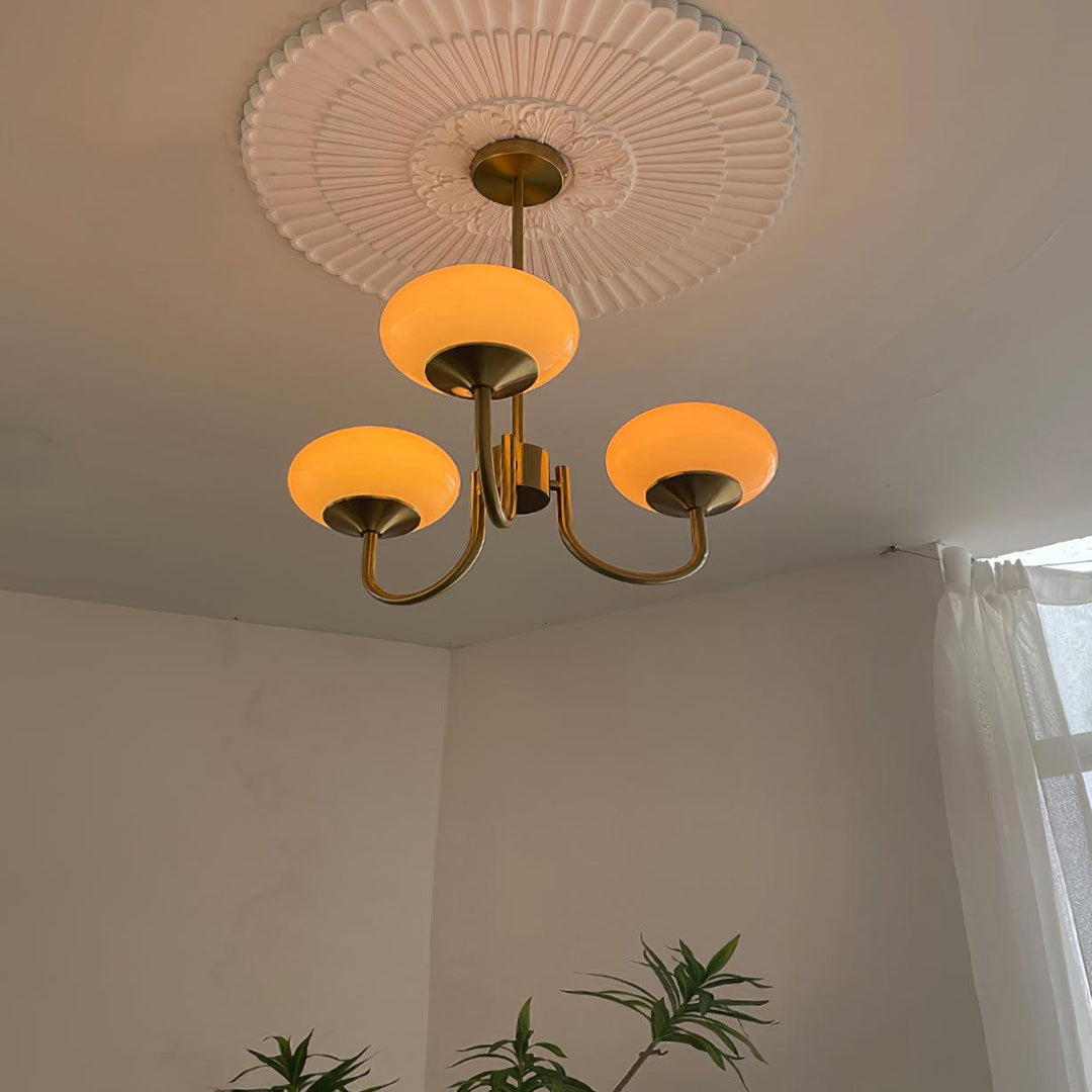 Goldene Kronleuchter mit drei leuchtenden Glaskugeln, Deckenrosette, modernes Design.