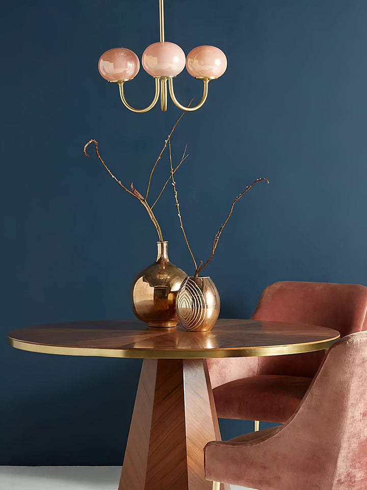 Rosa Kronleuchter über Holztisch, goldene Vasen, rosa Stuhl, modernes Wohnzimmerdesign.