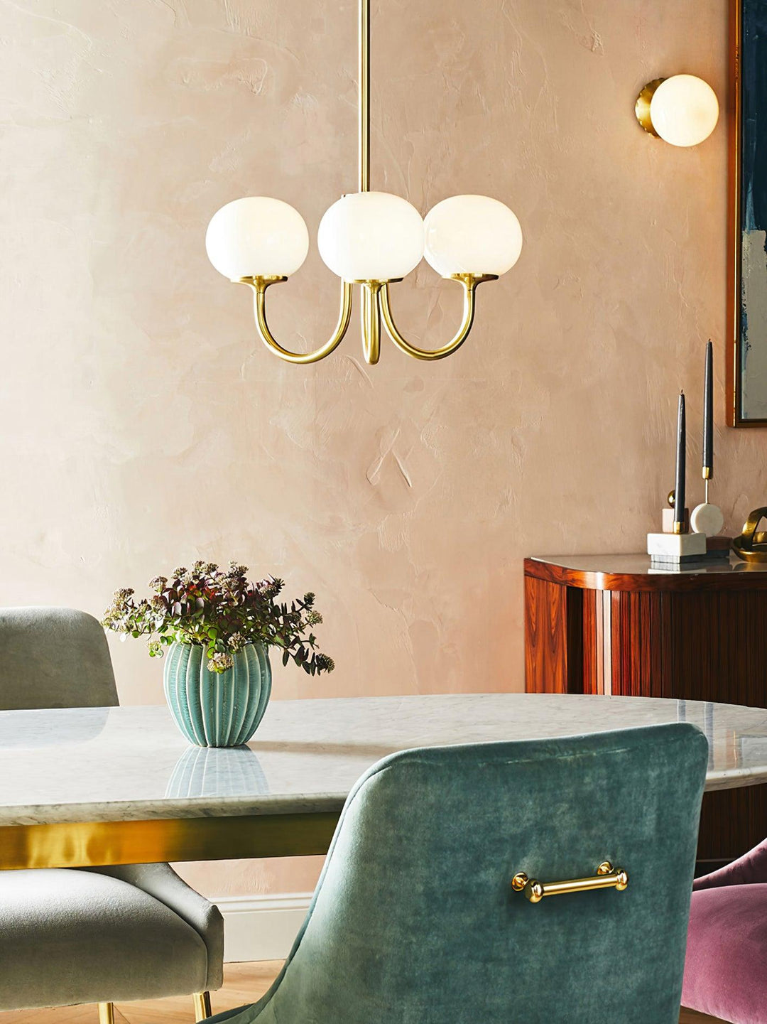 Goldene Kronleuchter mit weißen Glaskugeln über Marmortisch in modernem Esszimmer.