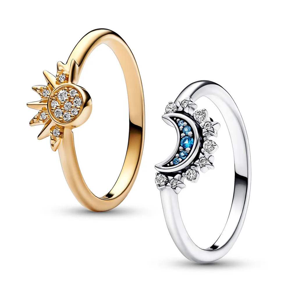 Zwei Ringe, goldener Sonnenring mit Diamanten, silberner Mondring mit blauen Steinen.
