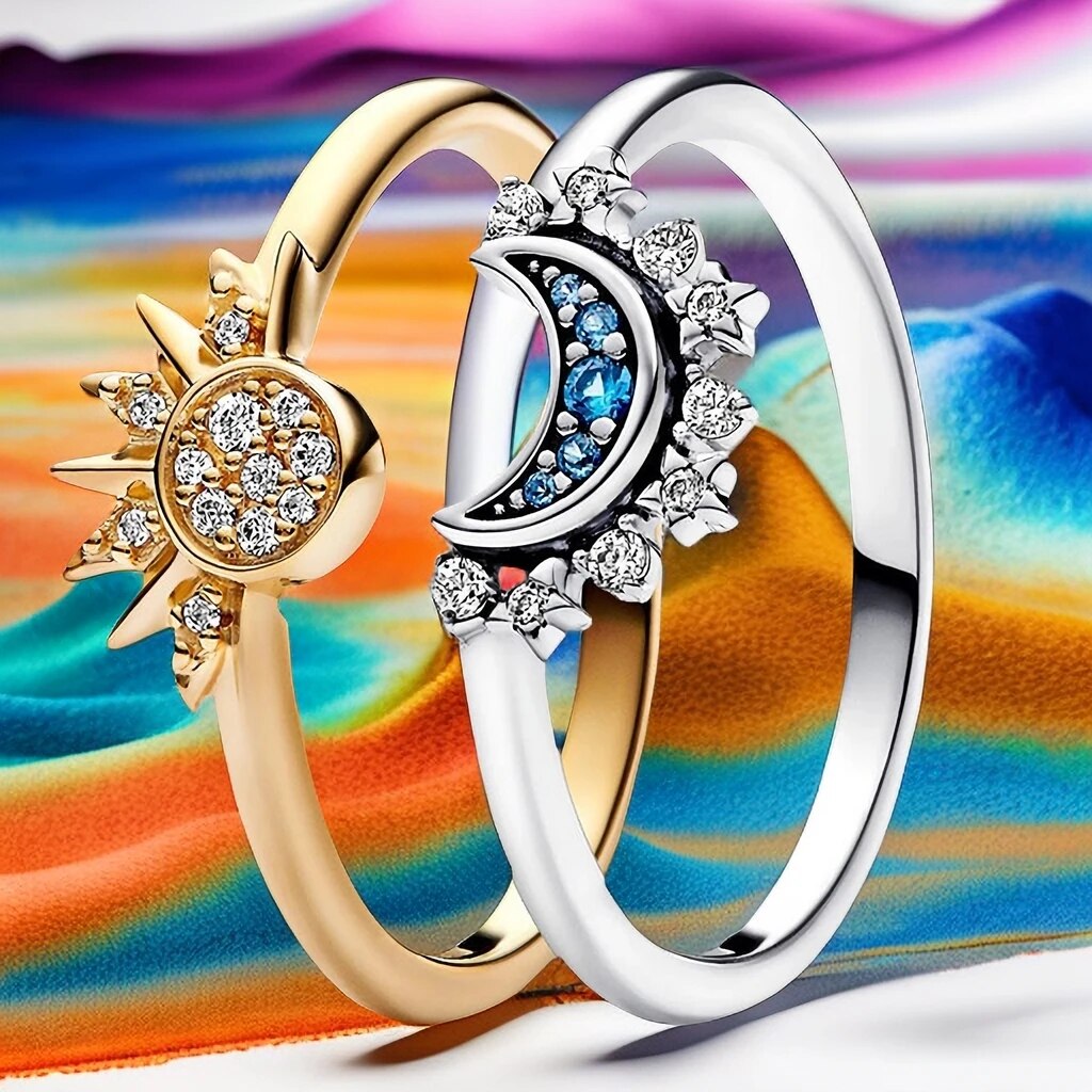Zwei Ringe mit Sonnen- und Mondmotiv, Gold und Silber, mit Diamanten, auf buntem Hintergrund.