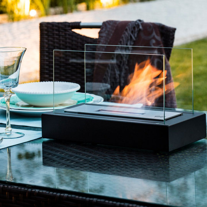 Tischkamin aus Glas und Metall, modern, für Outdoor-Dekoration, auf Glastisch im Garten.
