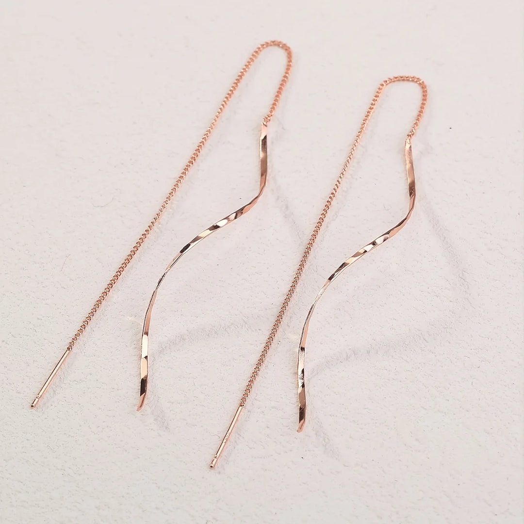 Roségoldene, lange Ohrringe mit geschwungenem Design, filigrane Kette, eleganter Schmuck.