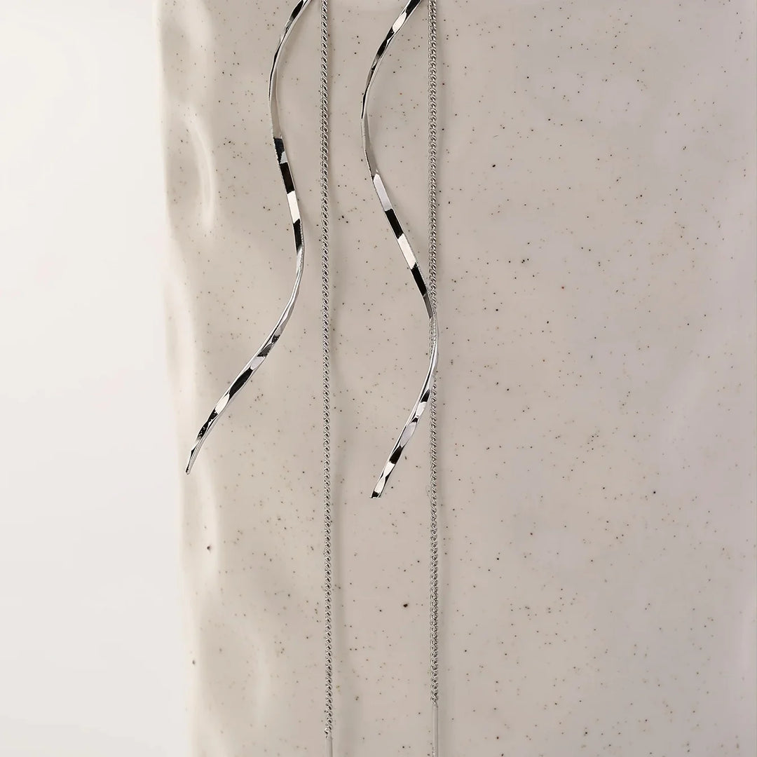 Silberne, lange Ohrringe mit schwarz-weißen Streifen auf hellem Hintergrund, minimalistisches Design.
