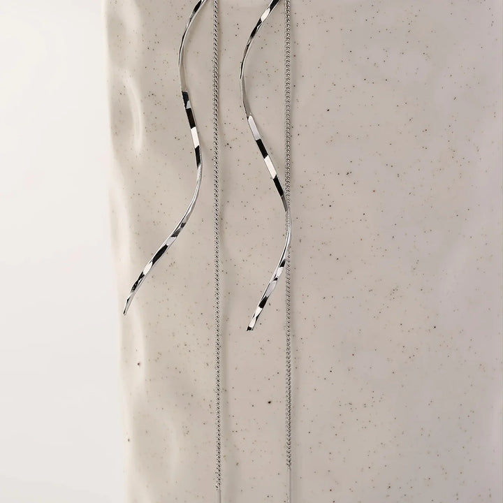 Silberne, lange Ohrringe mit schwarz-weißen Streifen auf hellem Hintergrund, minimalistisches Design.