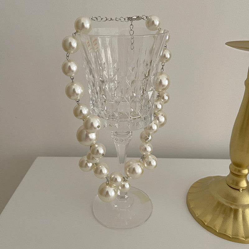 Perlenkette auf Kristallglas, elegante Dekoration, weiße Perlen, luxuriöses Schmuckdesign.