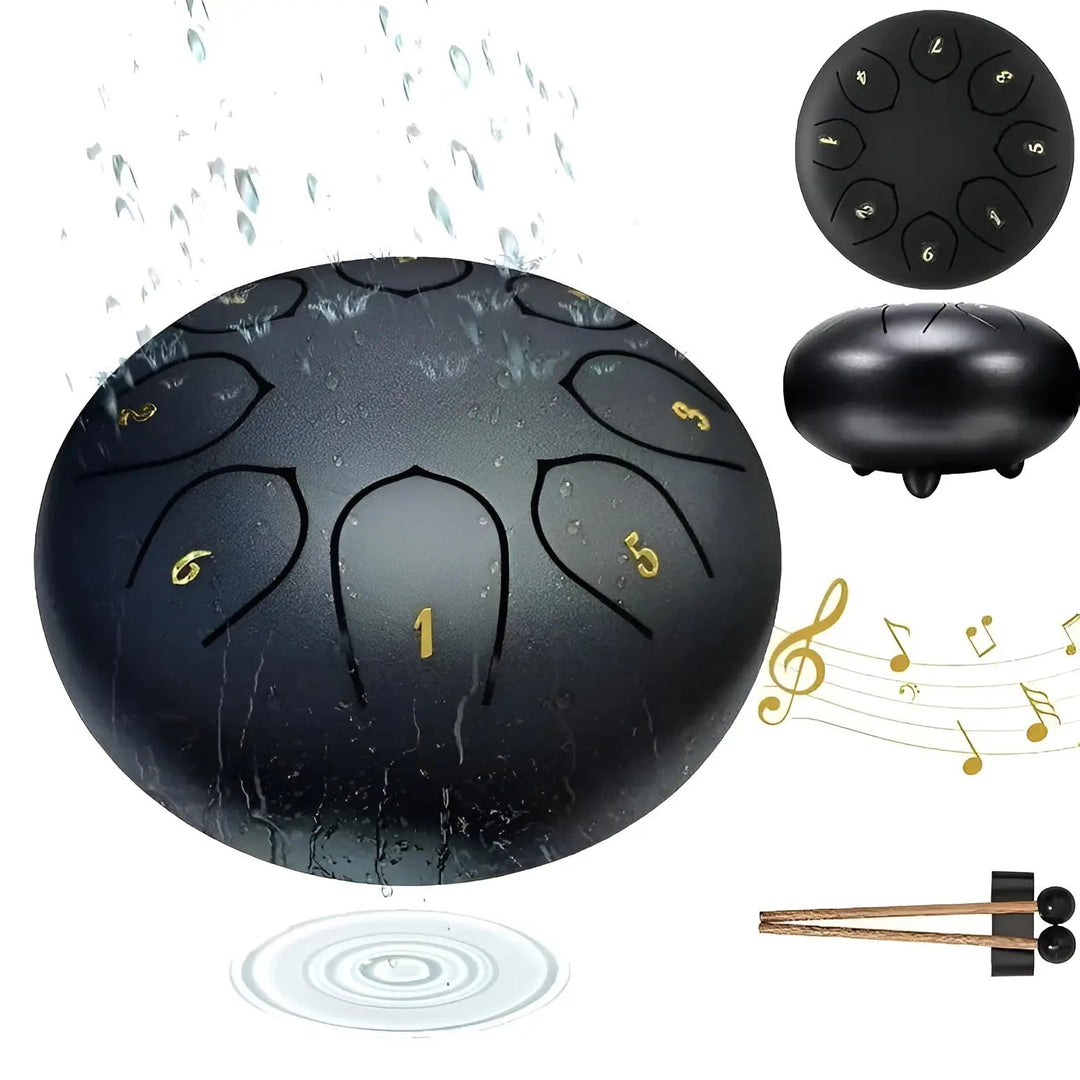 Schwarze Stahlzungentrommel mit Wasser, Noten und Schlägeln, ideal für Outdoor-Musik.