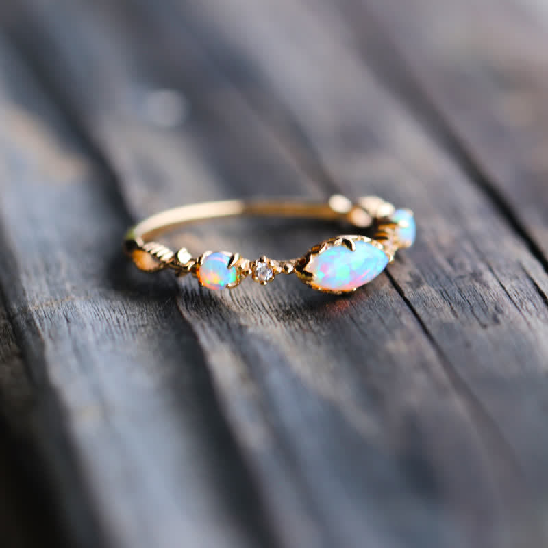 Goldener Opalring mit funkelnden Steinen auf Holzoberfläche, eleganter Schmuck, Damenaccessoire.