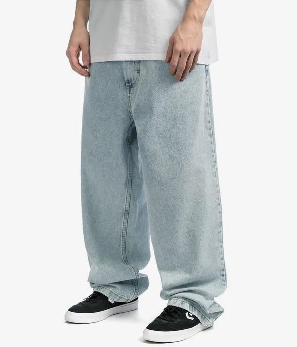 Mann trägt weite, hellblaue Jeans von Polar Skate Co., kombiniert mit schwarzen Sneakers.