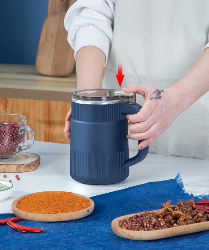 Person hält blauen elektrischen Mixer mit Griff in moderner Küche.