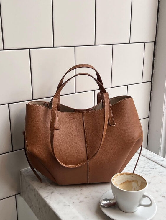 "Braune Leder Tote Bag auf Marmortisch, stilvolle Damenhandtasche, geräumig und vintage, ideal für Büro und Shopping."
