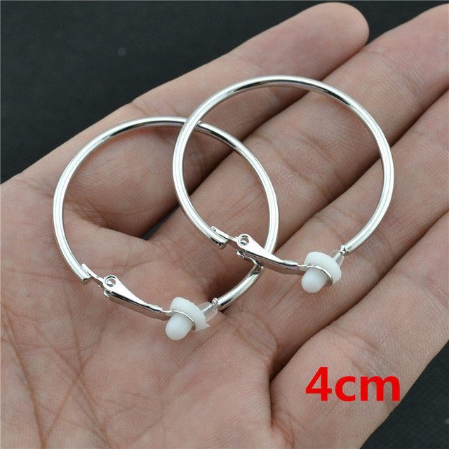 Silberne Clip-Ohrringe, 4 cm, ohne Piercing, klassischer Stil, auf Handfläche.