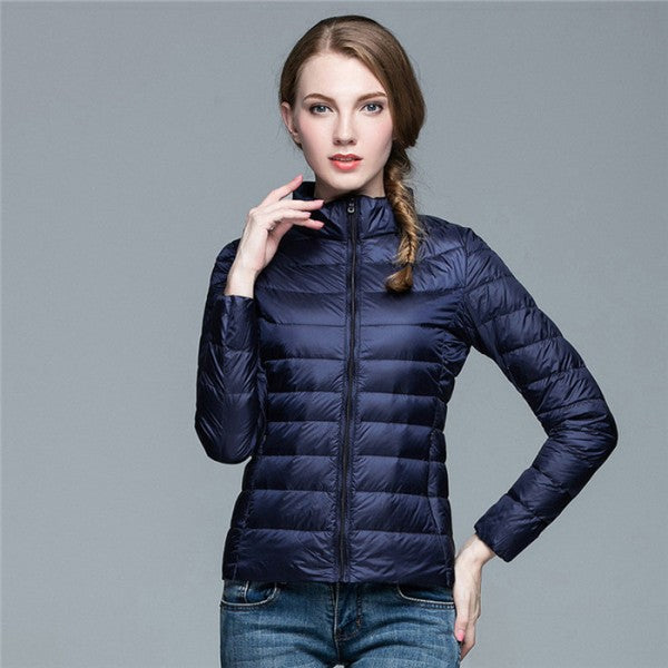 Frau in dunkelblauer Daunenjacke, Stehkragen, Reißverschluss, modisch, warm, Winterbekleidung.