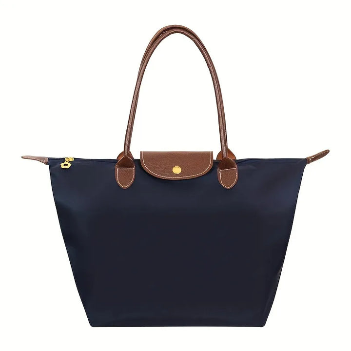 Dunkelblaue Damenhandtasche aus Nylon mit braunen Ledergriffen und Klappe.