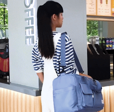 Frau mit blauer Reisetasche im Café, gestreiftes Shirt, moderne Reisetasche, Alltagstasche.