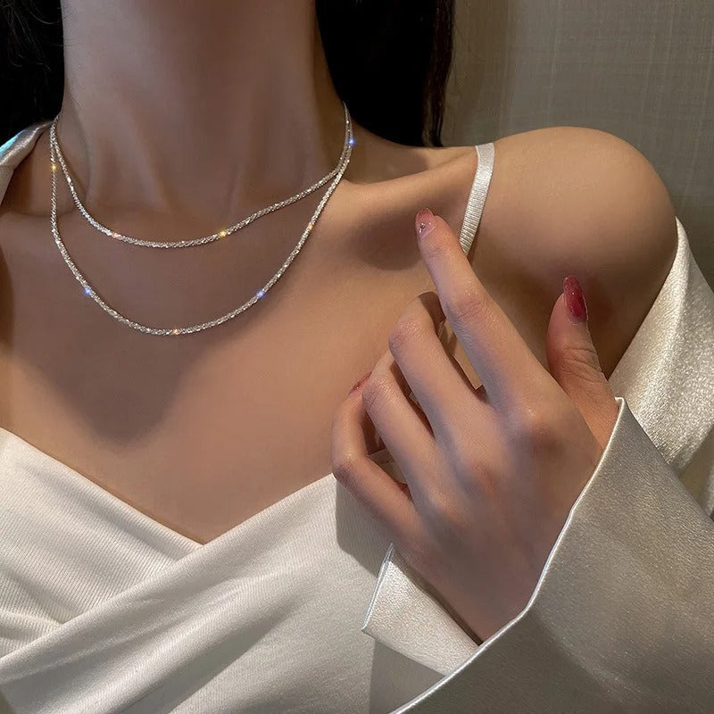 Frau trägt elegantes, silbernes Halsketten-Set auf weißem Satin-Kleid, modisches Schmuckdesign.