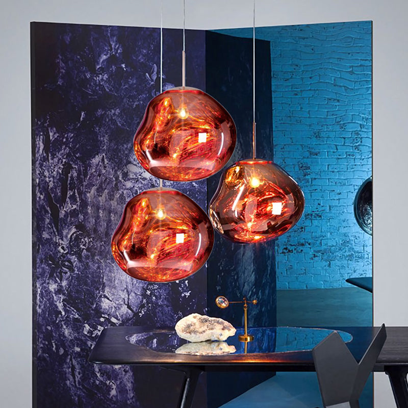 Drei moderne, kupferfarbene Pendelleuchten über einem Tisch, stilvolles Innendesign.