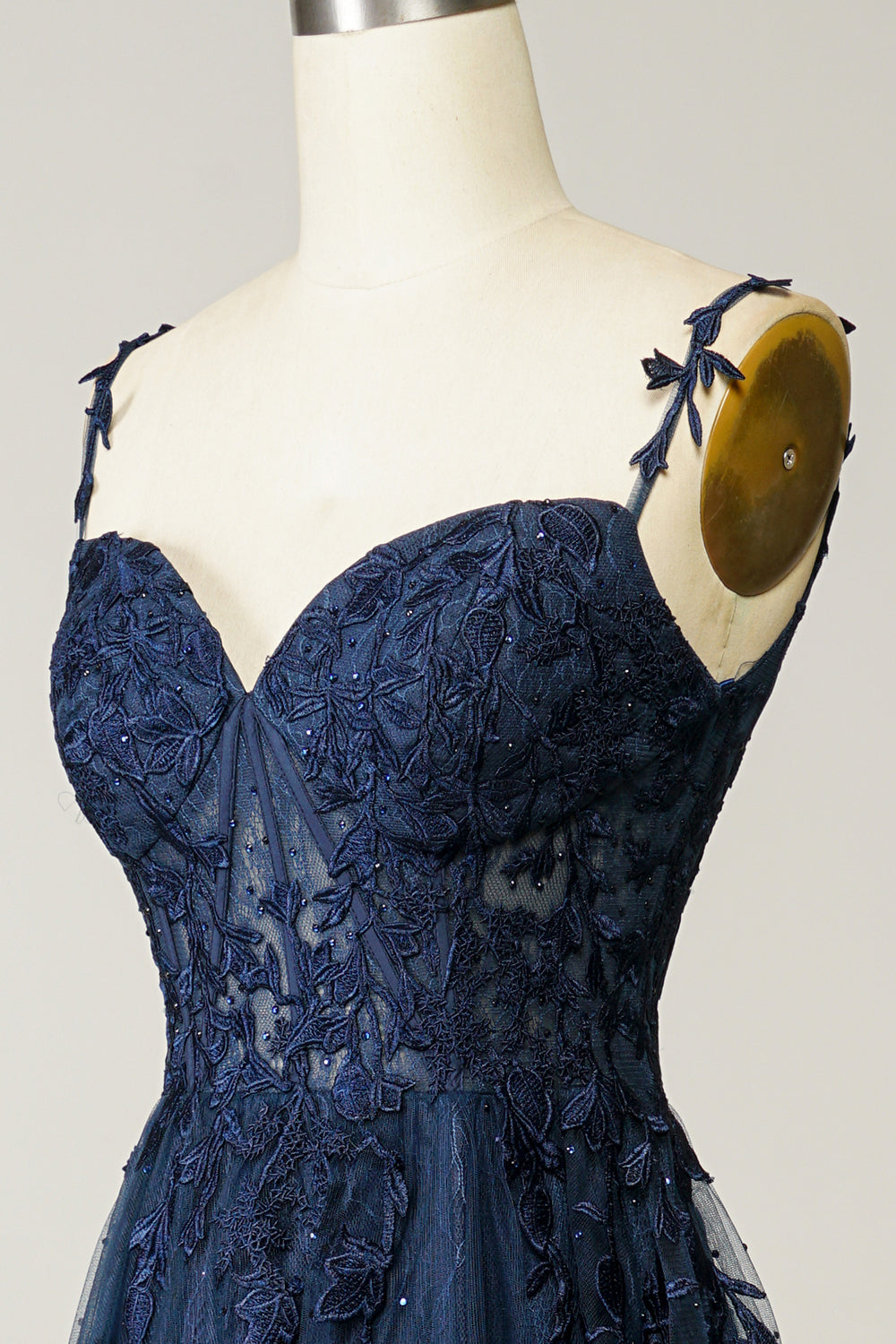 Dunkelblaues Abendkleid mit Spitzenapplikationen auf Schneiderpuppe, elegantes Design.
