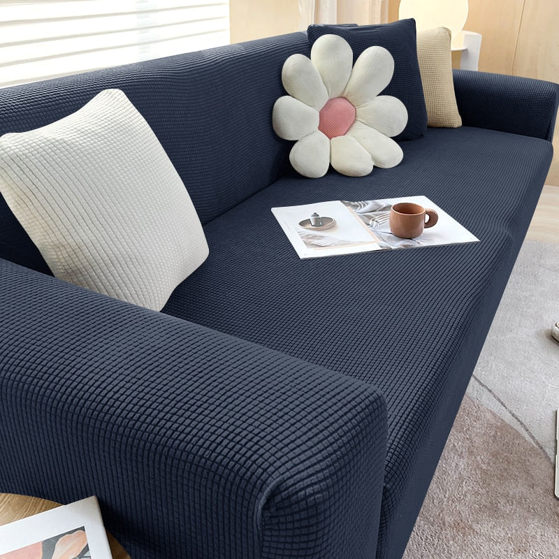 Dunkelblaues Sofa mit strukturiertem Stoff, dekoriert mit Kissen und Zeitschriften.