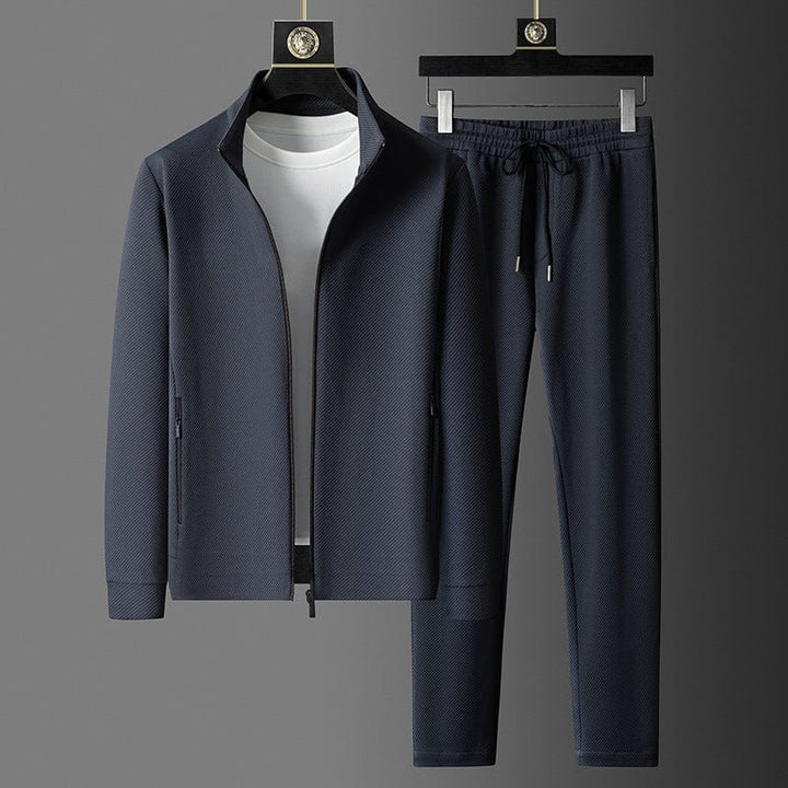 Dunkelgrauer Herren-Trainingsanzug mit Reißverschlussjacke und Jogginghose, sportlich, elegant.
