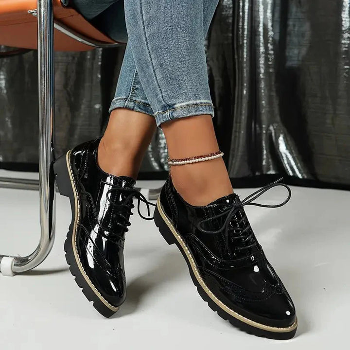 Elegante Damen-Lederpumps in glänzendem Lackleder mit Brogue-Details, vielseitig und komfortabel für jeden Anlass.