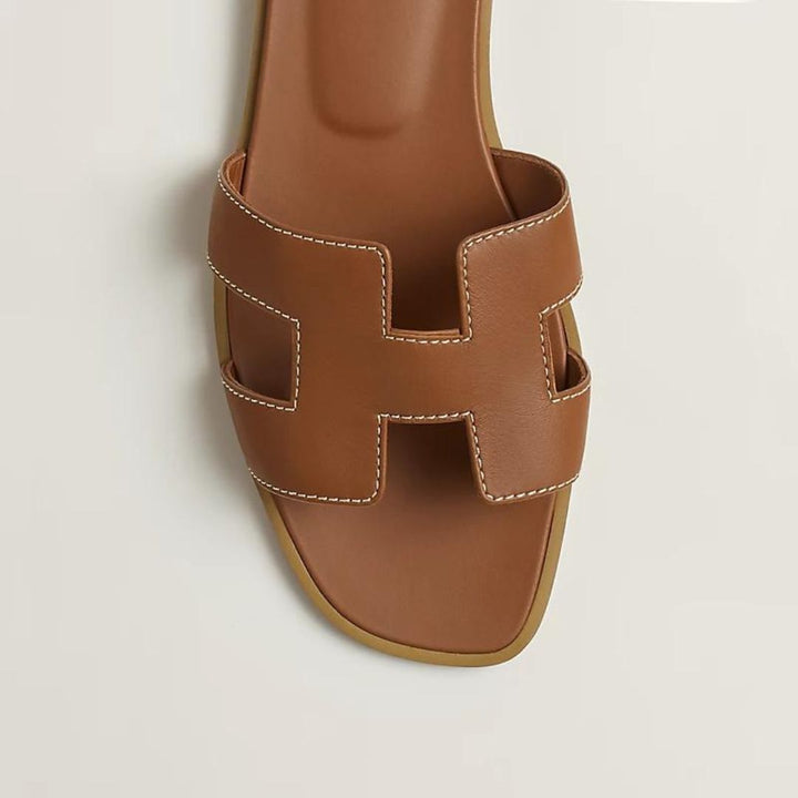 Elegante Luxussandalen für Damen mit verstellbaren Riemen, beiges Leder, flaches Design, ideal für Komfort und Stil.