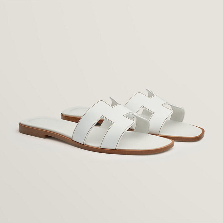 Elegante Luxussandalen für Damen mit verstellbaren Riemen, beiges Leder, flaches Design, ideal für Komfort und Stil.