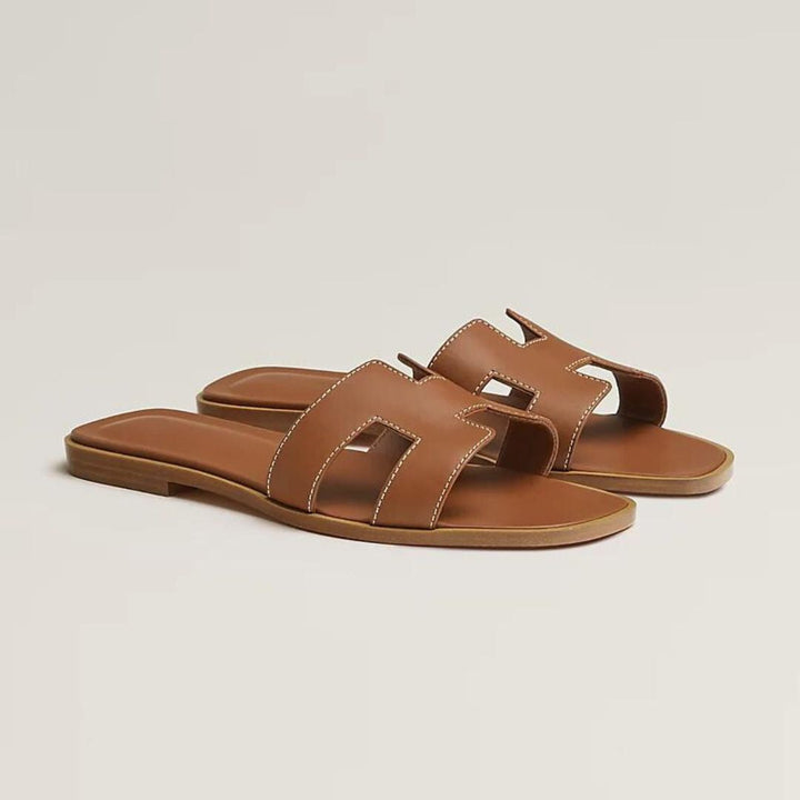 Elegante Luxussandalen für Damen mit verstellbaren Riemen, beiges Leder, flaches Design, ideal für Komfort und Stil.