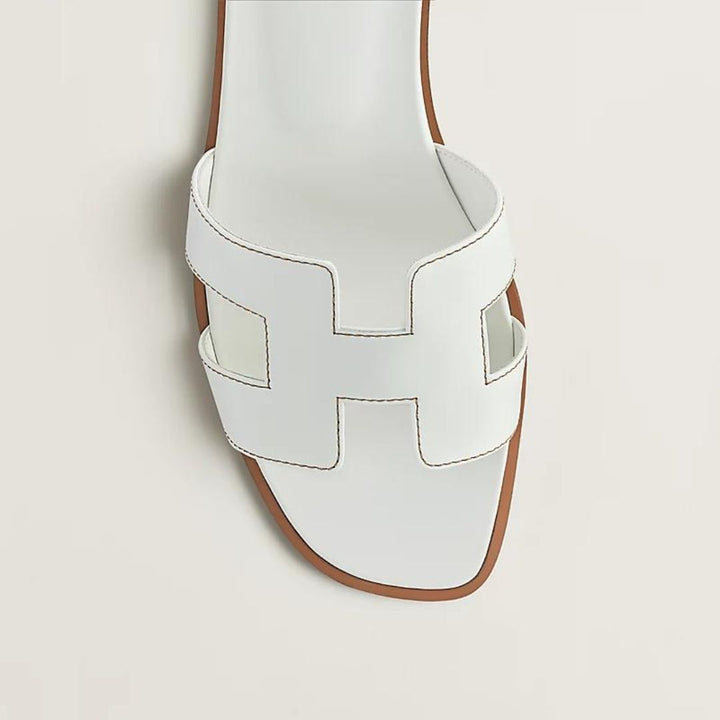 Elegante Luxussandalen für Damen mit verstellbaren Riemen, beiges Leder, flaches Design, ideal für Komfort und Stil.