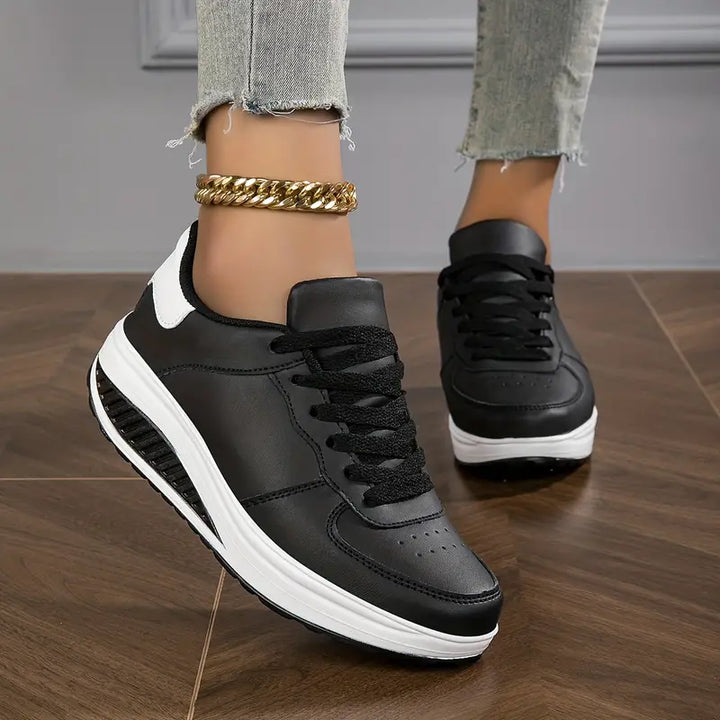 Schwarze Damen-Sneaker mit weißer Sohle, Lederoptik, goldene Fußkette, Jeans.
