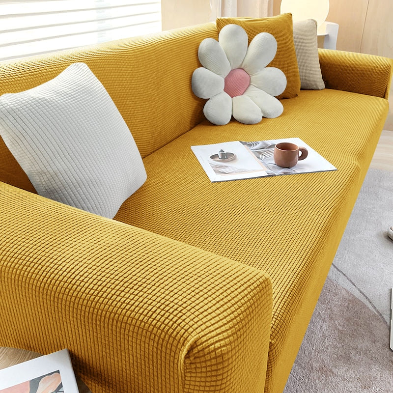 Gelbes Sofa mit strukturiertem Stoff, dekoriert mit weißen Kissen und Blümchenkissen.