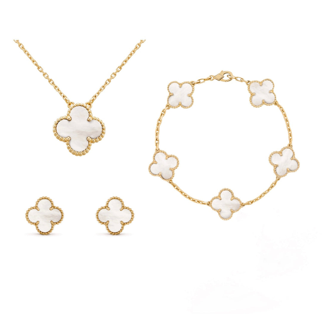 Goldene Schmuckset mit weißem Kleeblatt-Design: Halskette, Armband, Ohrringe.