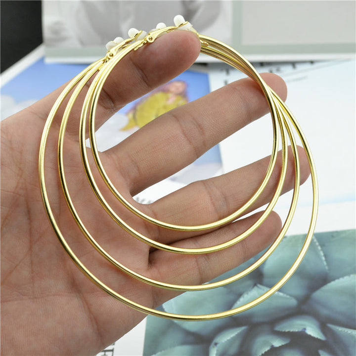 Goldene Creolen, Clip-Ohrringe, ohne Stecker, klassisch, trendig, Modeschmuck, Hand gehalten.