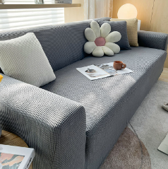 Graues Sofa mit kariertem Bezug, dekoriert mit Kissen und Zeitschriften, modernes Wohnzimmer.
