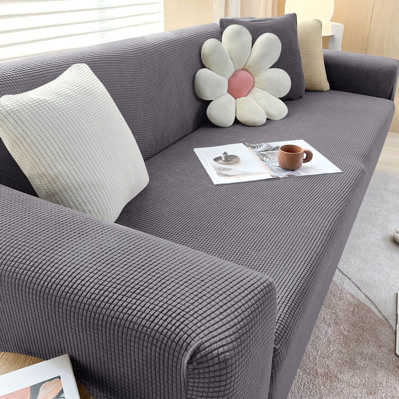 Graues Sofa mit strukturiertem Stoff, dekoriert mit Kissen, Blume, modernem Wohnzimmer.