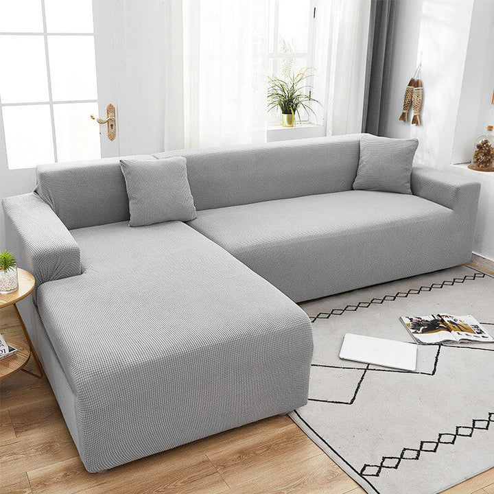 Graues Ecksofa mit Kissen im modernen Wohnzimmer, Holzfußboden, helle Einrichtung.