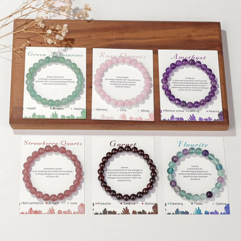 Sechs Edelstein-Armbänder auf Karten: Aventurin, Rosenquarz, Amethyst, Erdbeerquarz, Granat, Fluorit.