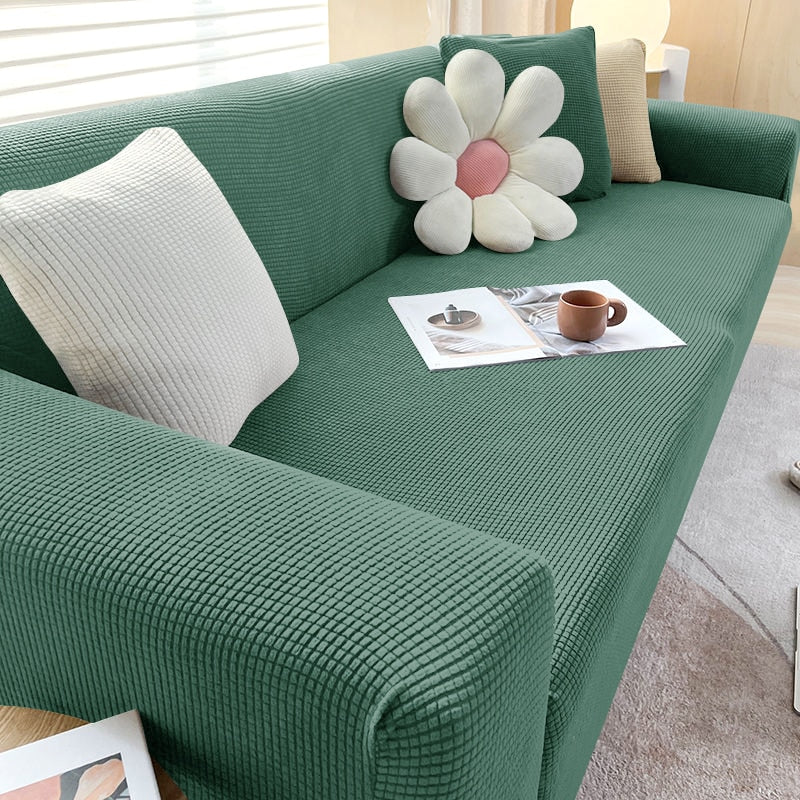 Grünes Sofa mit strukturiertem Stoff, dekoriert mit Kissen und Zeitschriften, modernes Wohnzimmer.